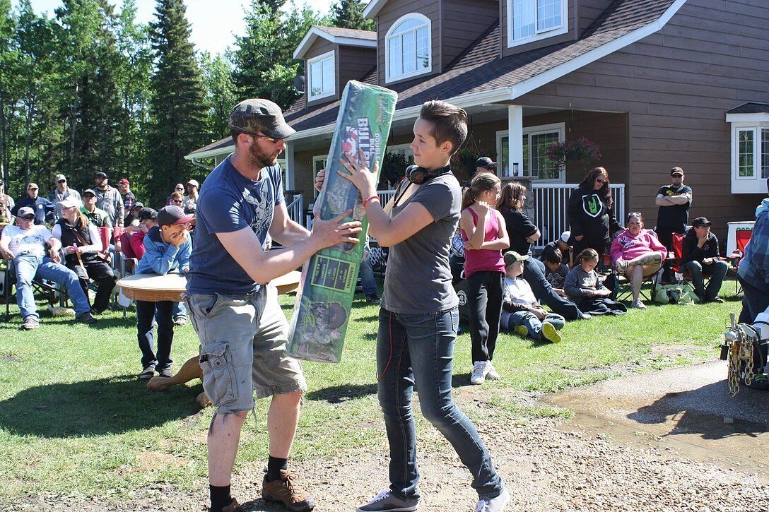 A man and a woman are holding a blanket in front of a house.
