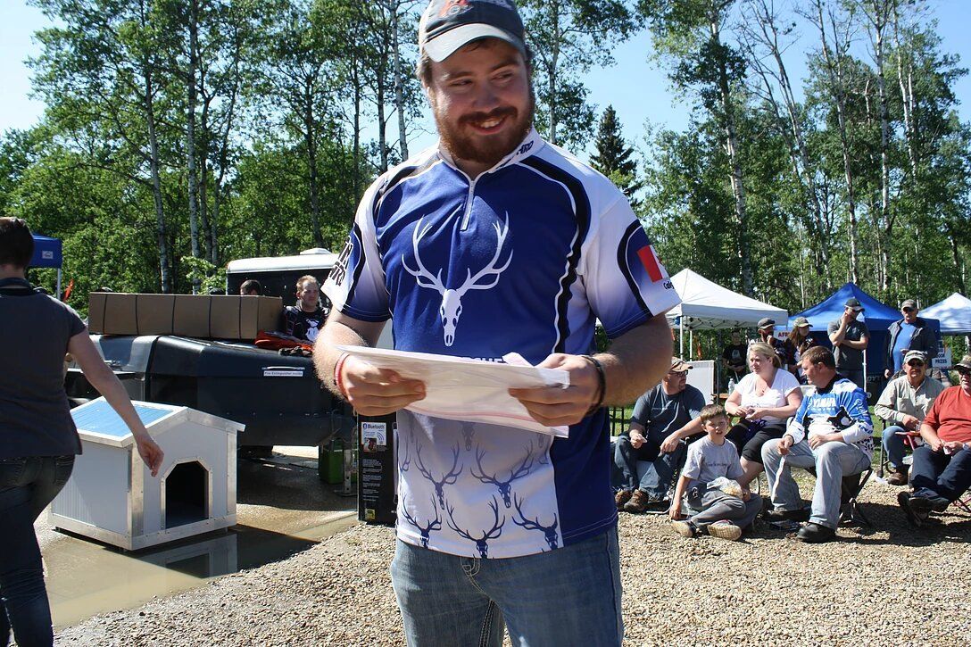 A man in a blue and white shirt is holding a piece of paper.