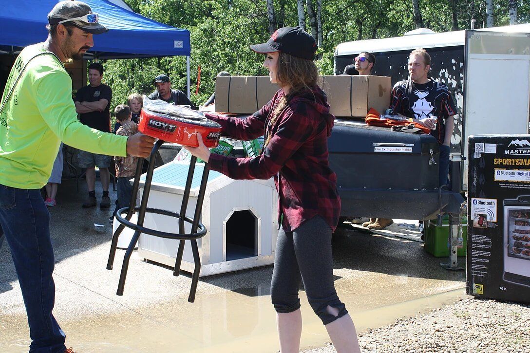 A man and a woman are holding a stool in front of a dog house.