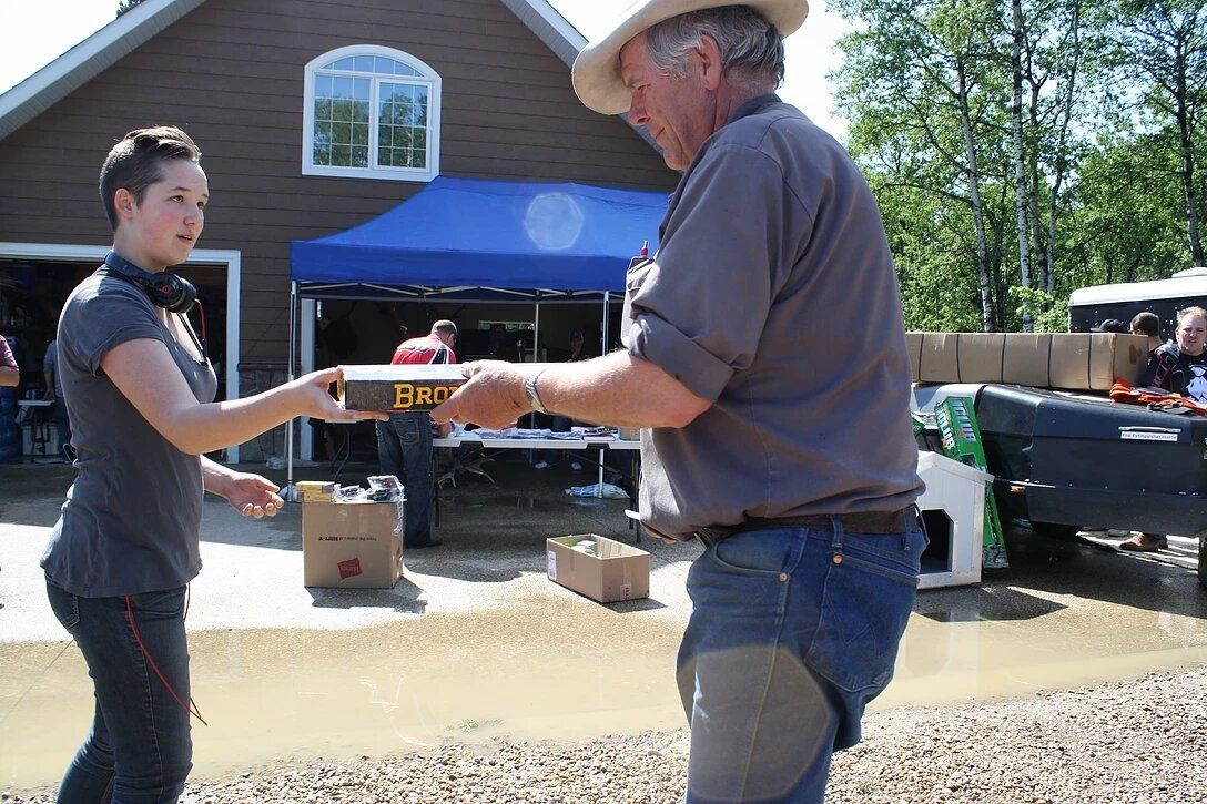 A man in a cowboy hat is handing a box to a woman
