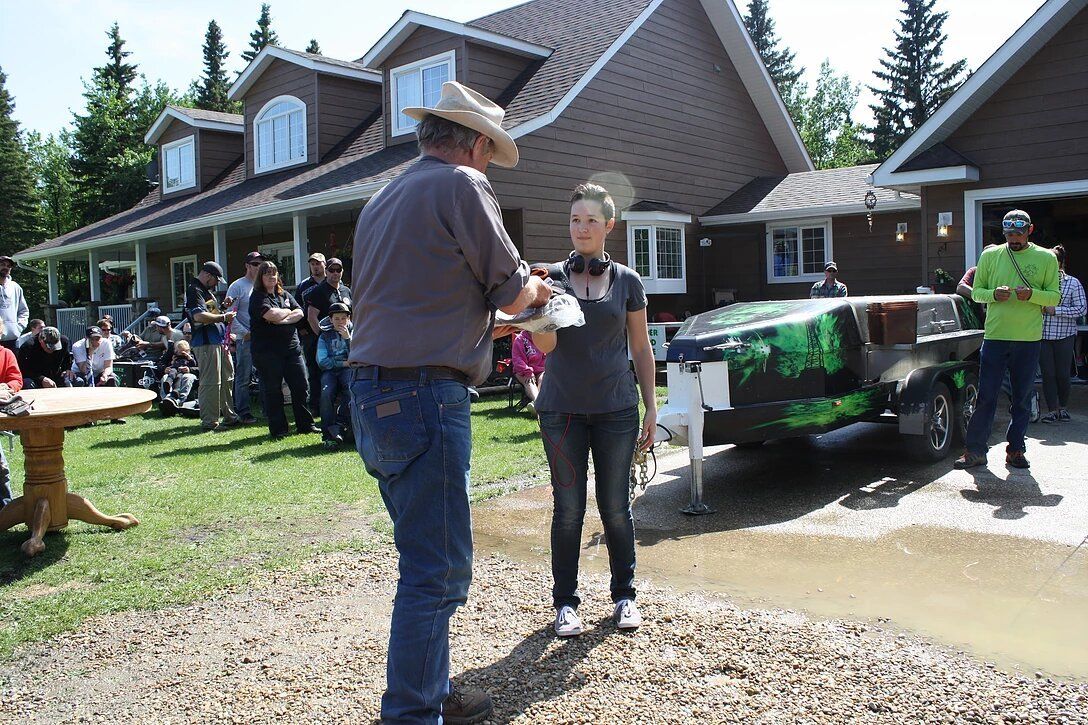 A man in a cowboy hat is talking to a woman in front of a house