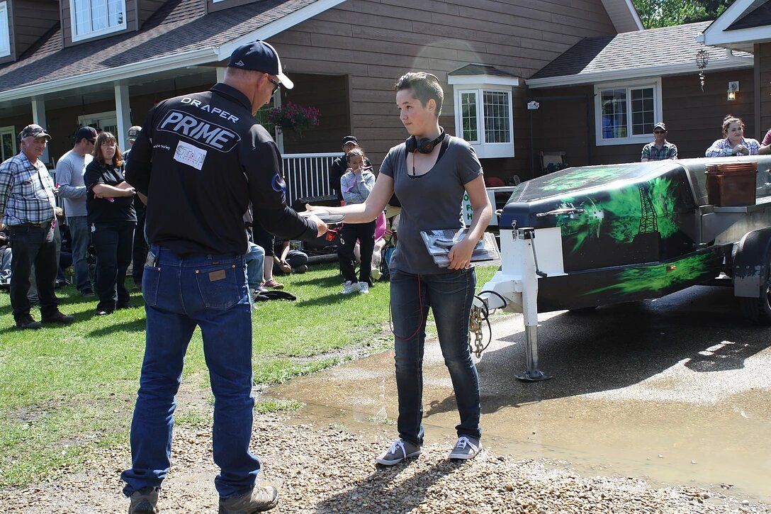 A man and a woman are shaking hands in front of a house