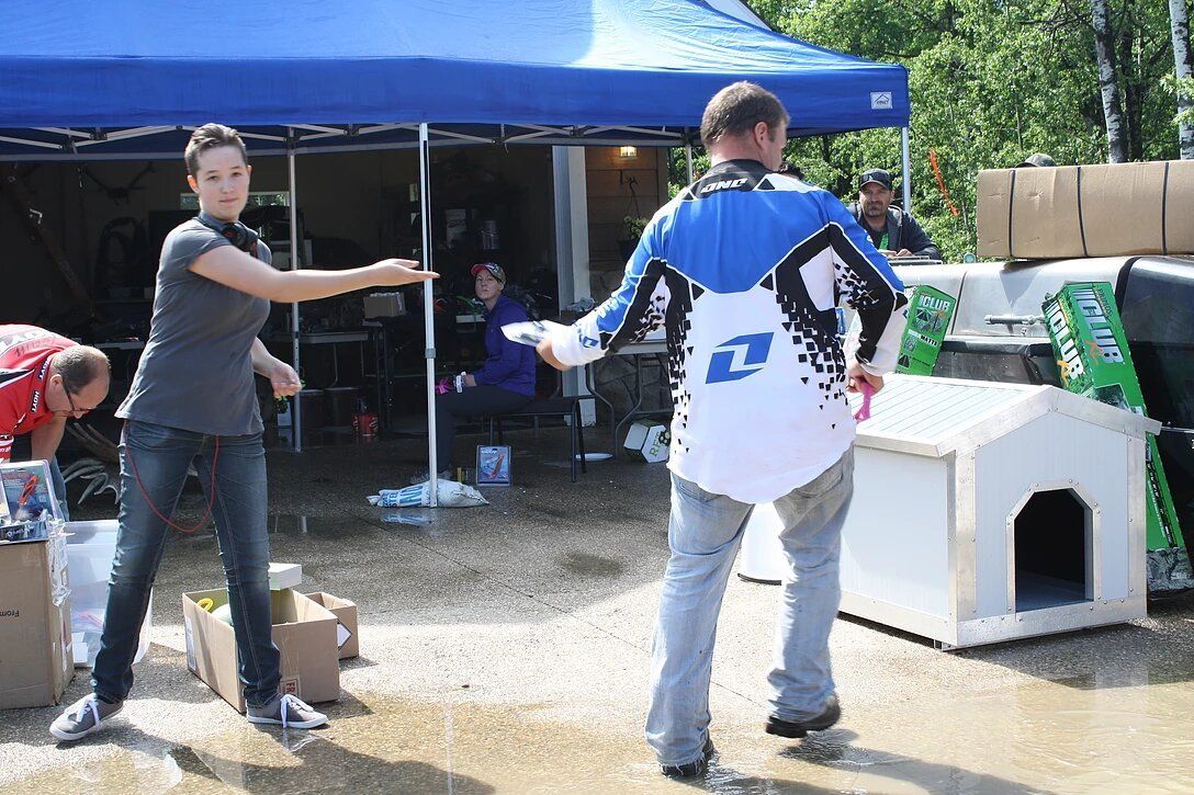 A man and a woman are standing in front of a blue tent.