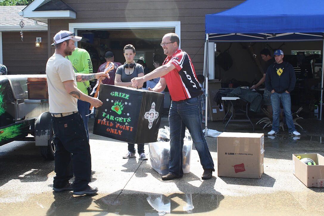 A group of people are standing in front of a garage holding a sign that says field tour