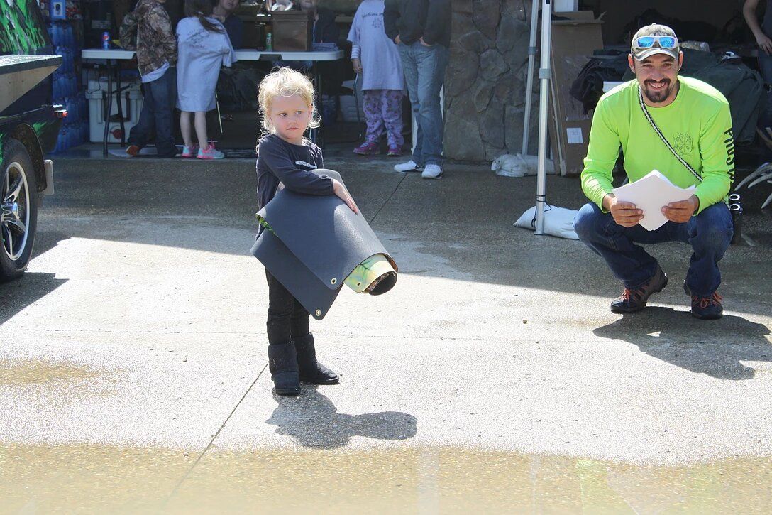 A little girl is standing on the sidewalk next to a man in a neon green shirt.
