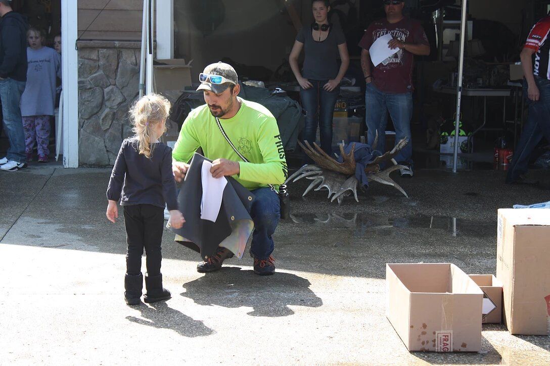 A man in a green shirt is kneeling down next to a little girl.