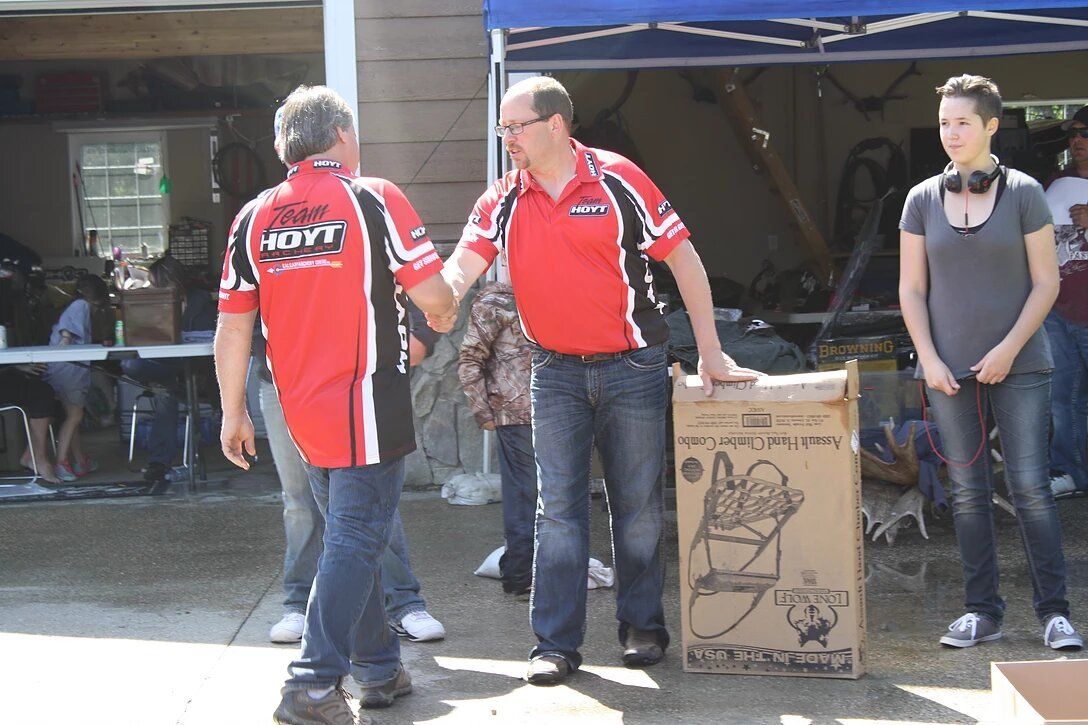 A man in a red shirt with the word hayt on it shakes hands with another man