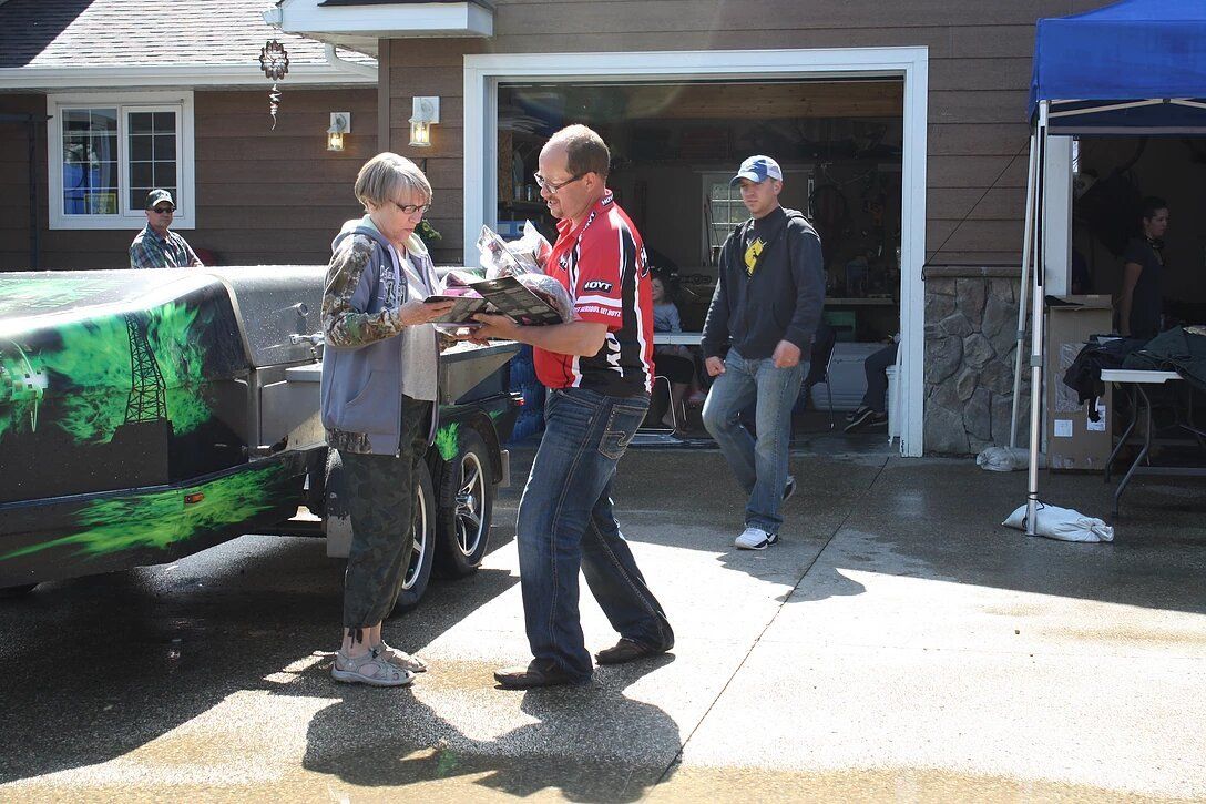 A man in a red shirt is talking to a woman in front of a truck