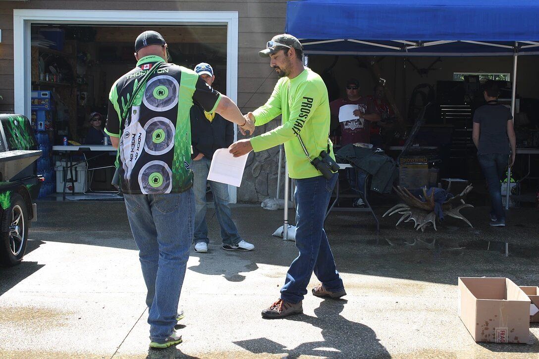 A man in a green shirt is shaking hands with another man.