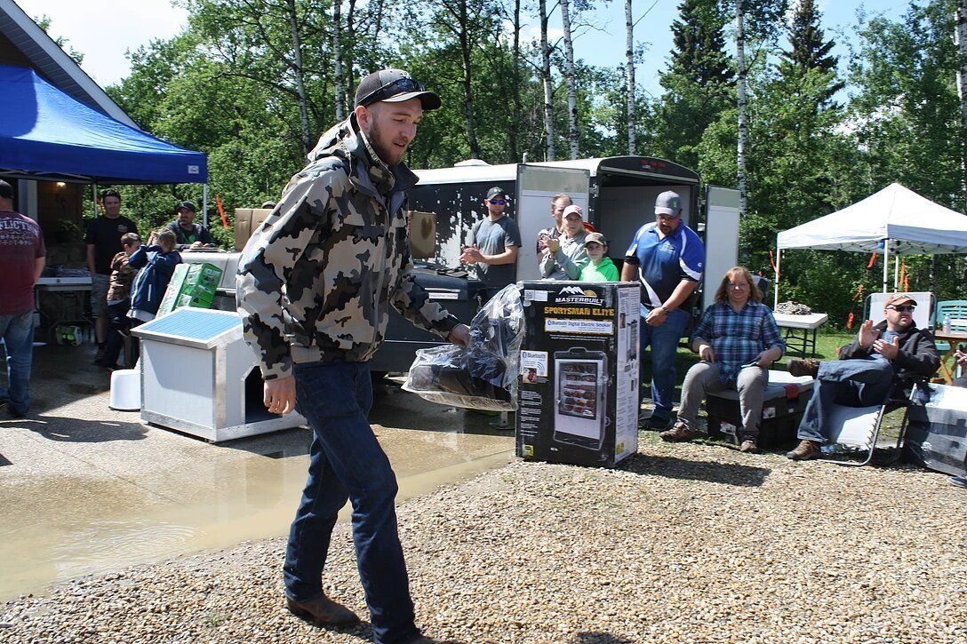 A man in a camo jacket is walking through a puddle of water.