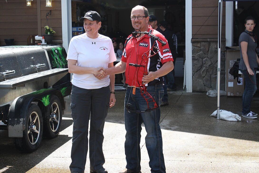 A man and a woman are shaking hands in front of a trailer.