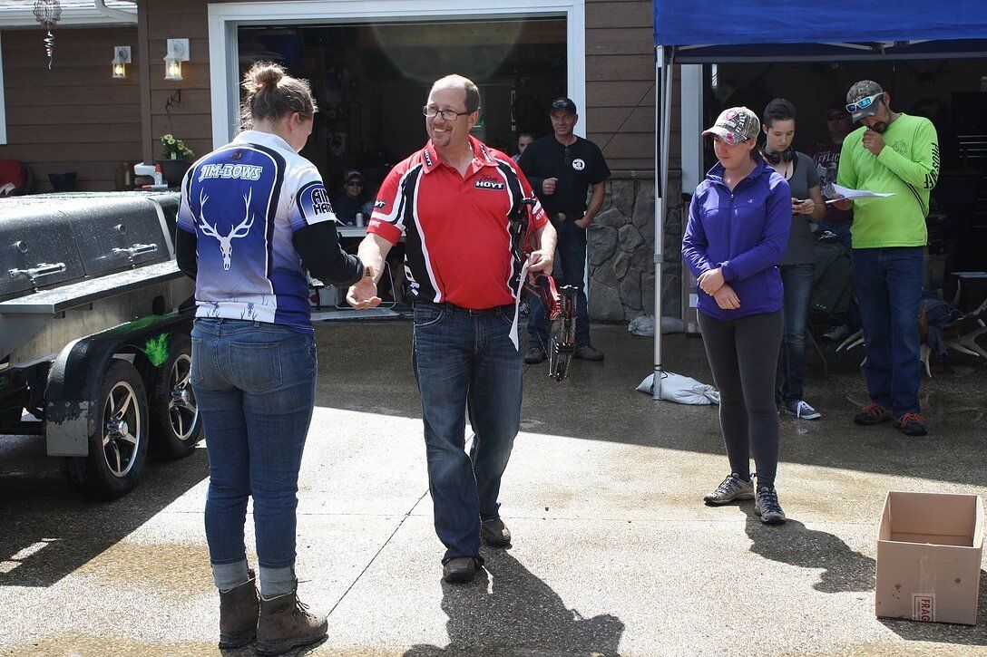 A man in a red shirt is shaking hands with a woman in a blue shirt.