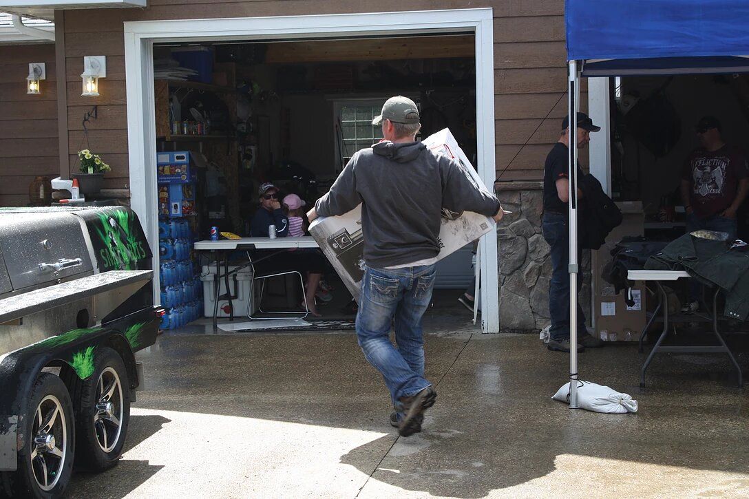 A man is carrying a large piece of paper in front of a garage door.