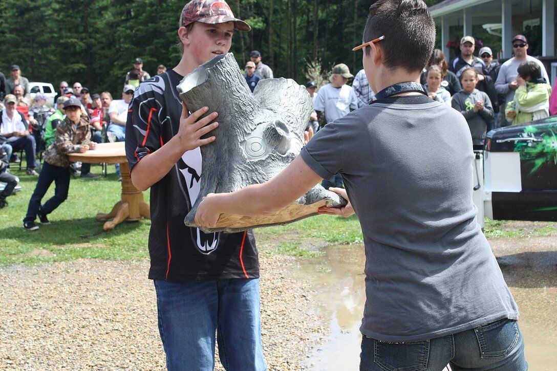 Two young boys are holding a large metal object in their hands.