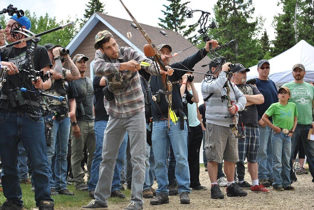A group of people are standing in front of a building holding bows and arrows.