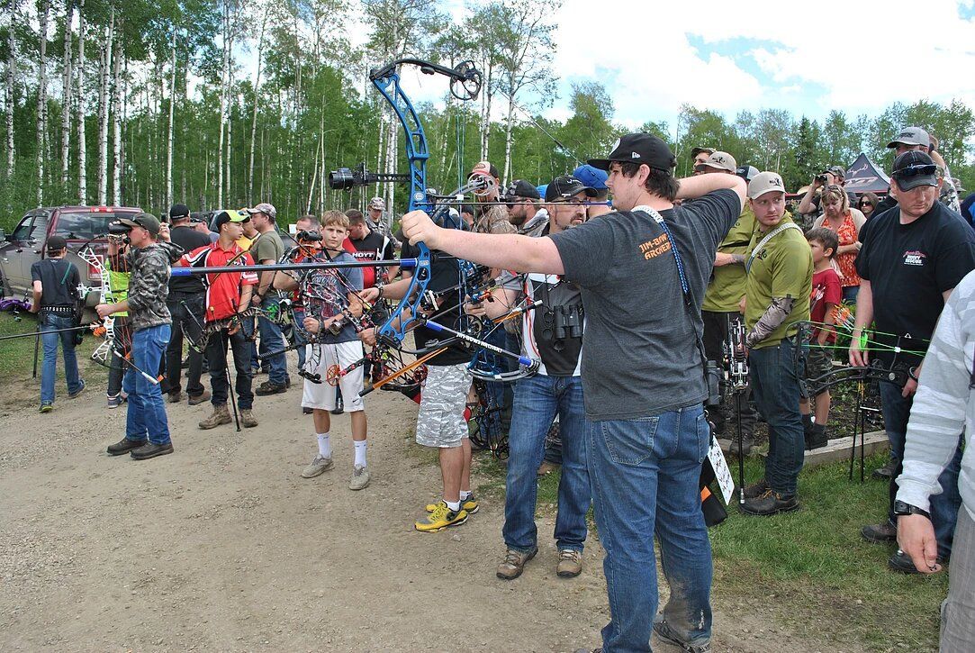 A group of people are standing in a field holding bows and arrows.