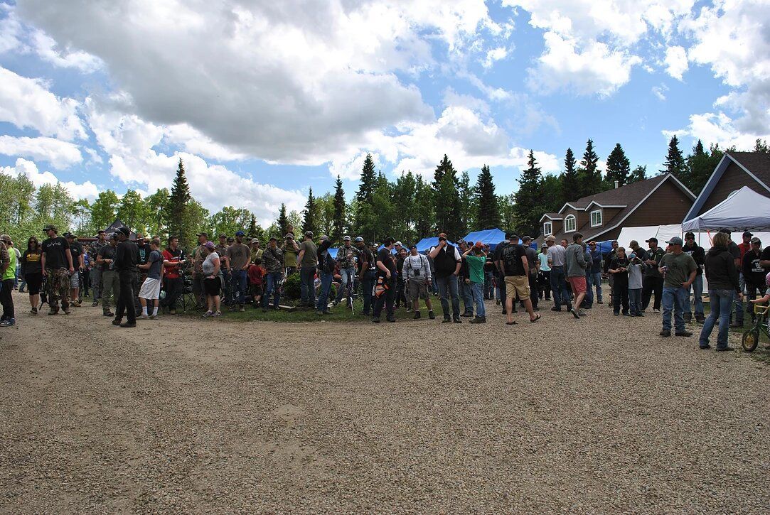 A large group of people are standing in a gravel area.