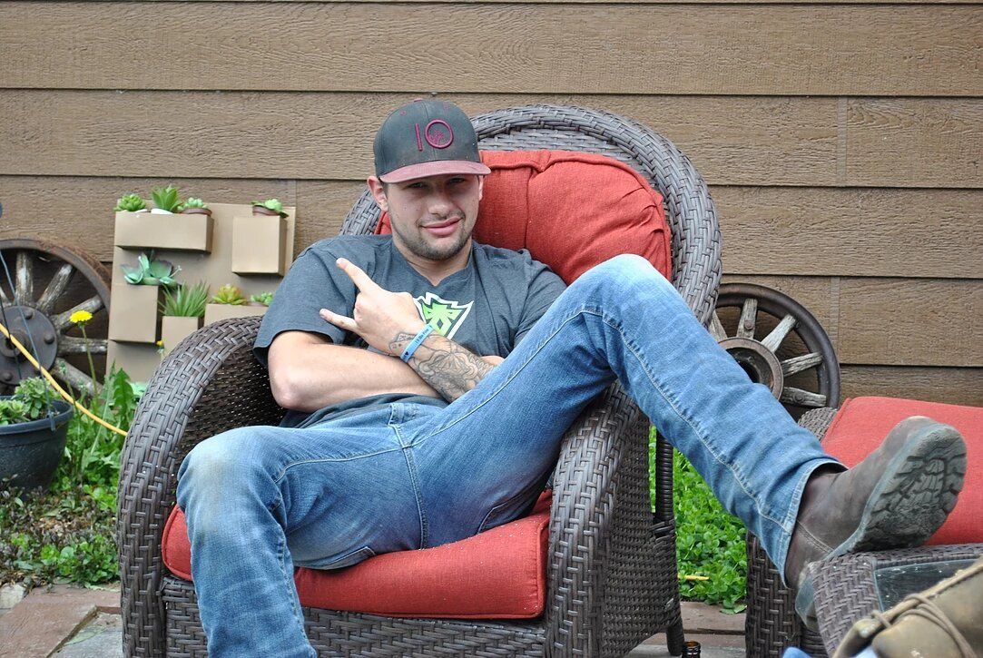 A man is sitting in a wicker chair with his legs crossed.