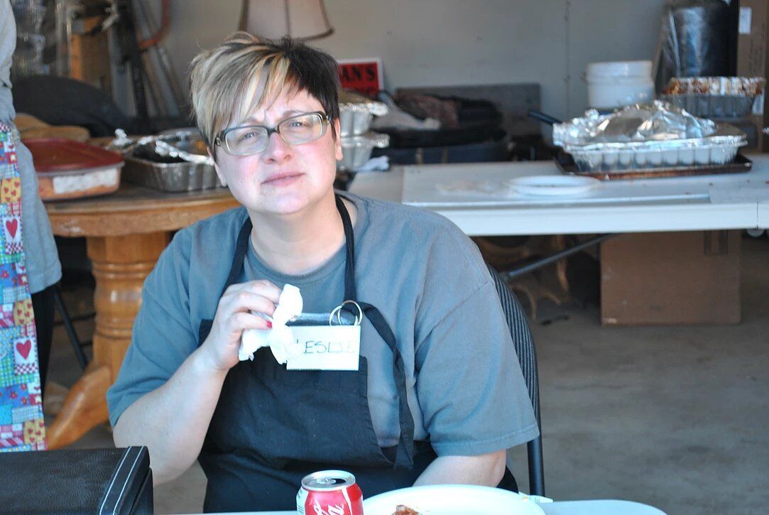 A woman sitting at a table with a plate of food and a can of soda
