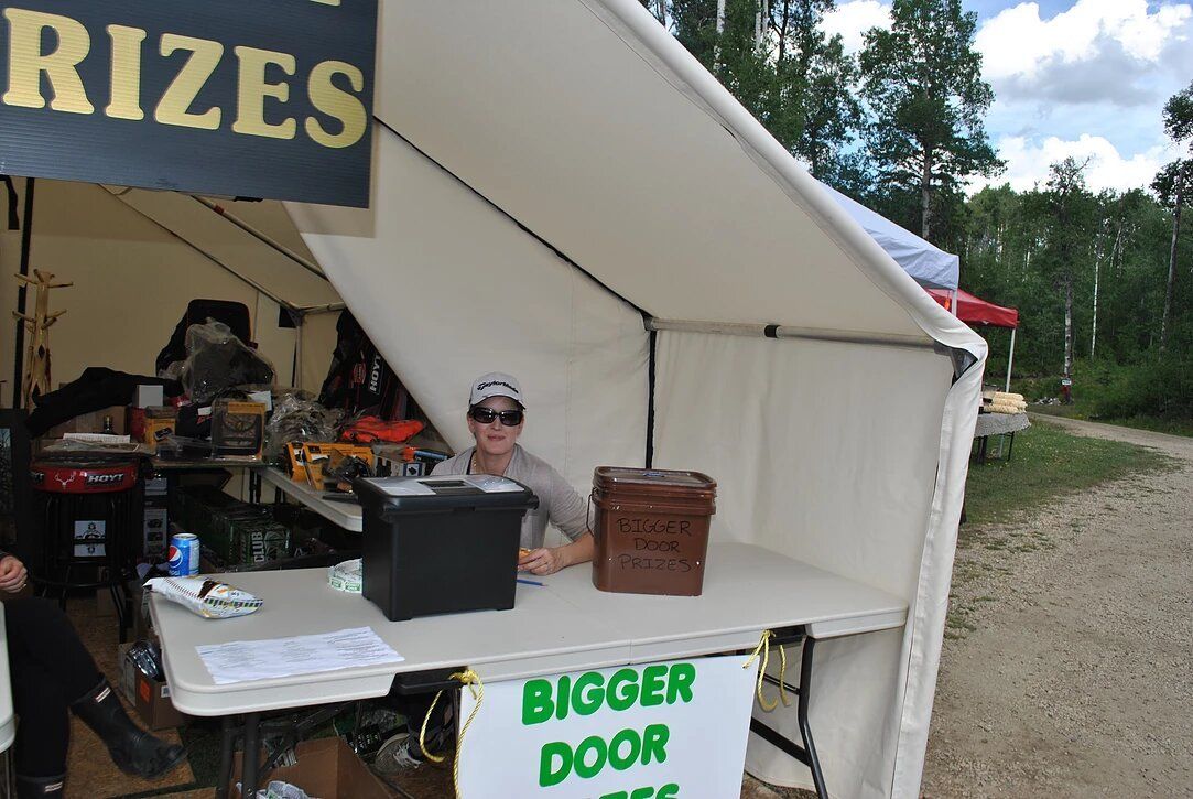 A man sitting at a table under a tent with a sign that says rizes