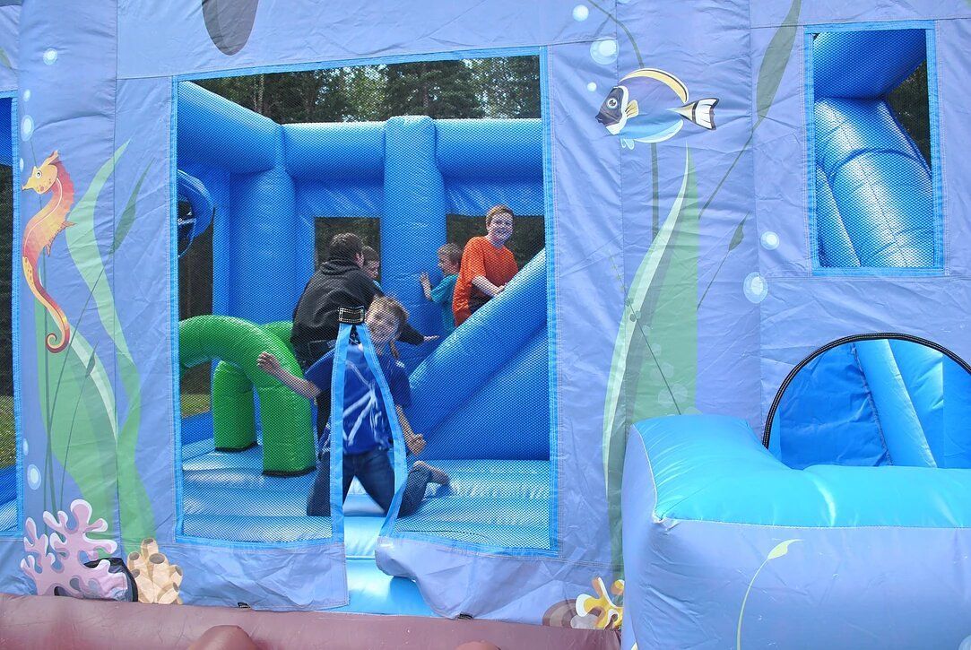 A group of children are playing in a blue bouncy house.