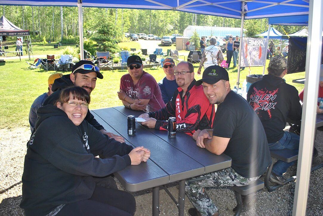 A group of people are sitting at a picnic table under a tent.