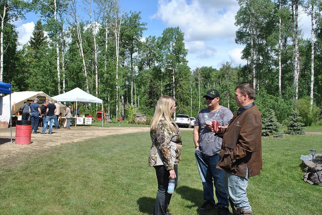 A group of people are standing in a grassy field talking to each other.
