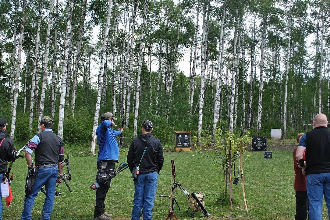 A group of people are standing in a field holding bows and arrows.