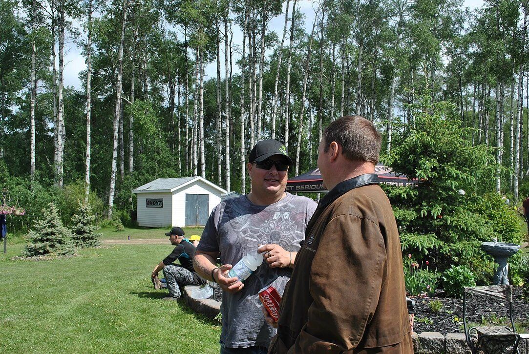 Two men are standing in a field talking to each other.