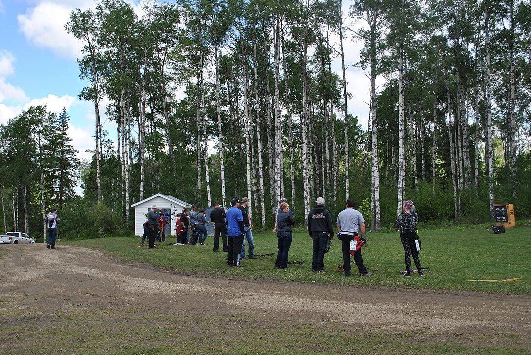 A group of people standing in a field with trees in the background