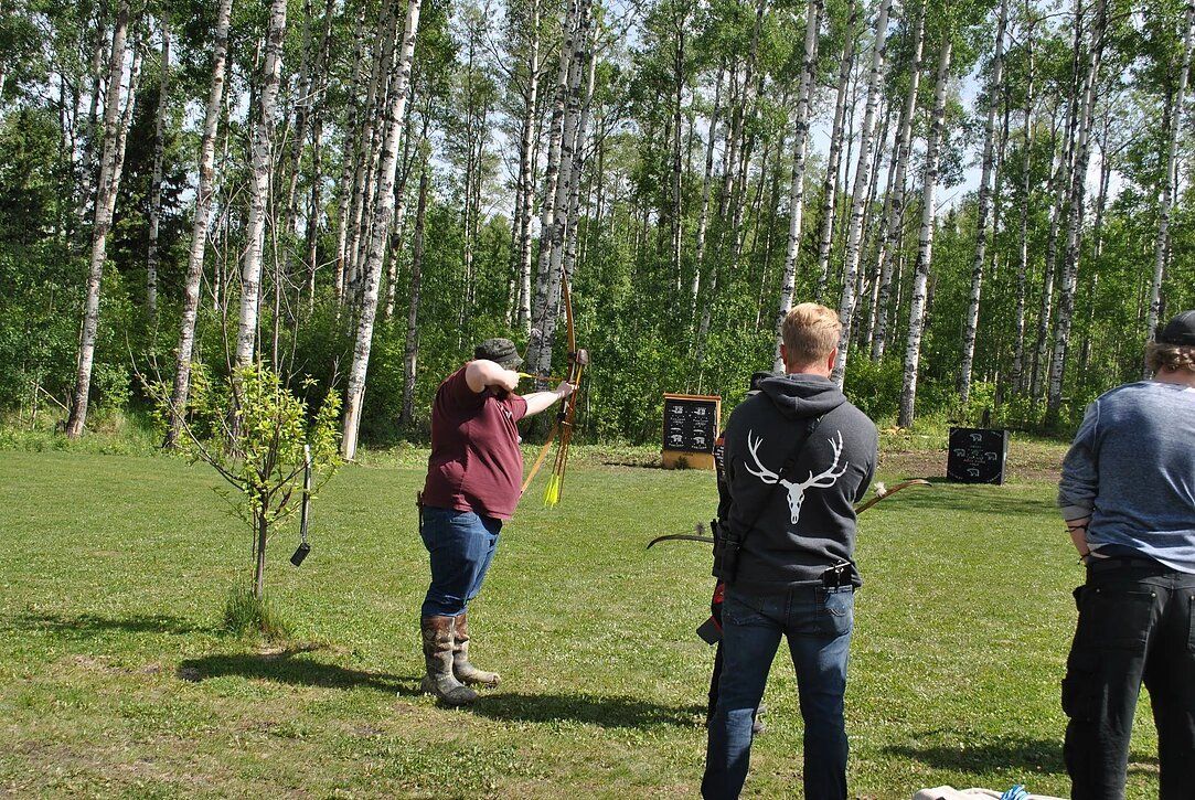 A group of people are standing in a field holding bows and arrows.