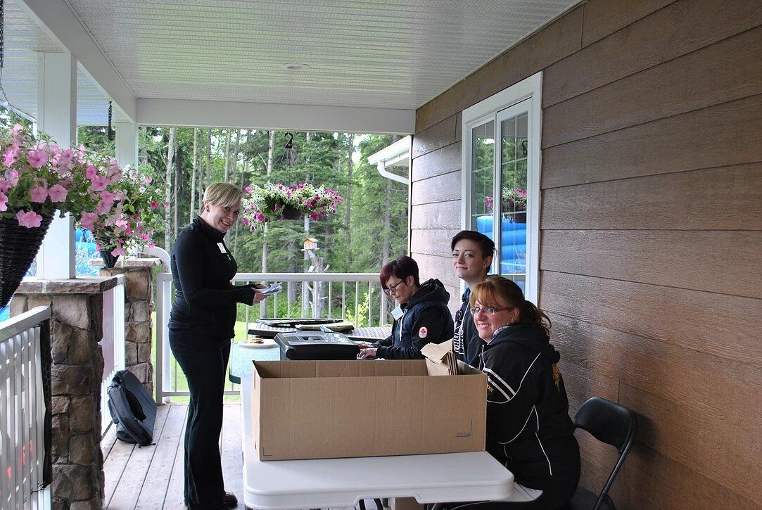 A group of people are sitting at a table on a porch.