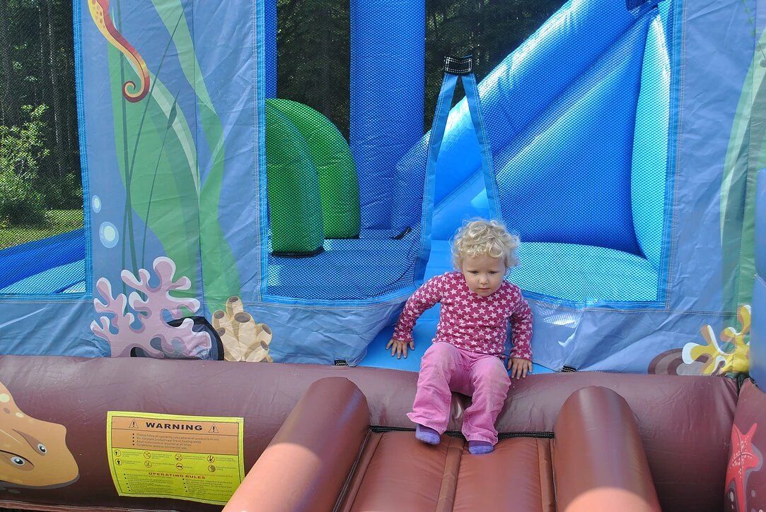 A little girl is sitting on a bouncy house