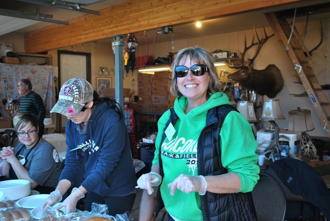 A woman in a green hoodie is standing in a room with other people.