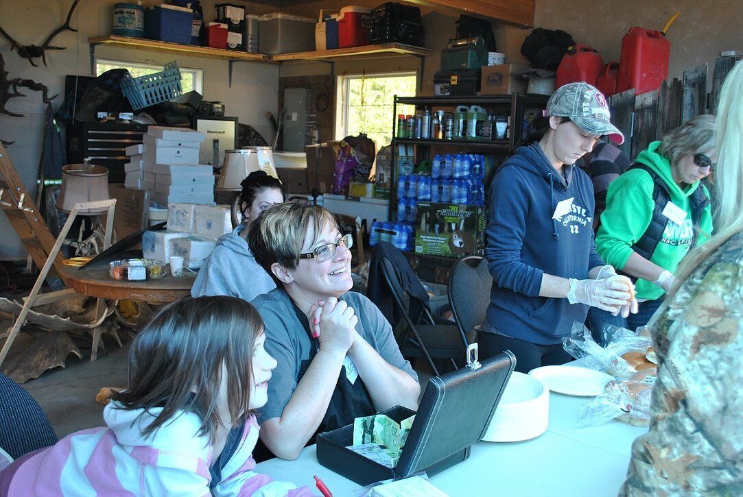 A group of people sitting around a table with a laptop