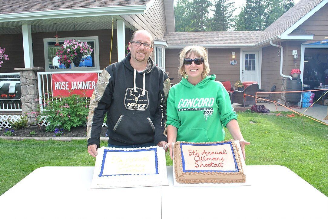 A man and a woman are standing next to a table with two cakes on it