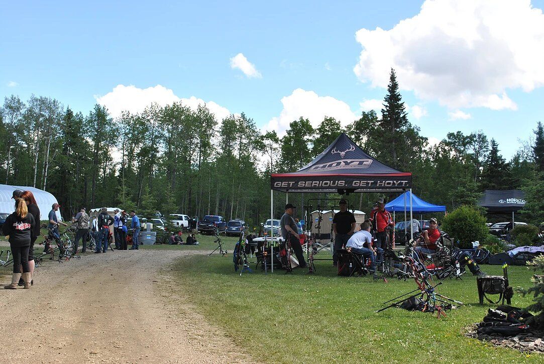 A group of people are gathered in a grassy area under a tent.