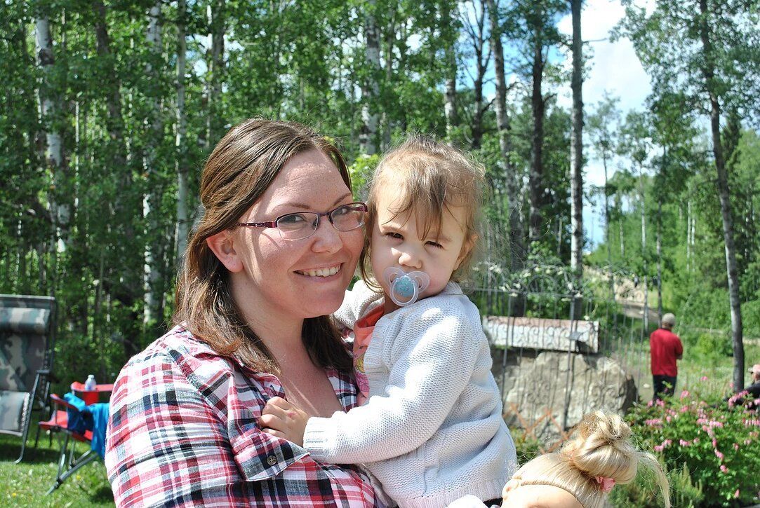 A woman is holding a baby with a pacifier in her mouth.