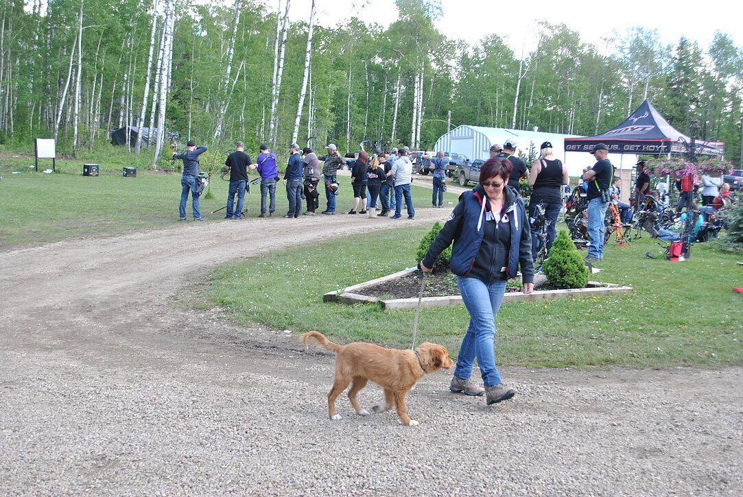 A woman is walking a dog on a dirt road.