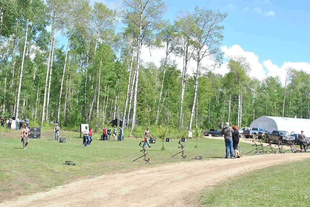 A group of people are standing in a field with trees in the background.