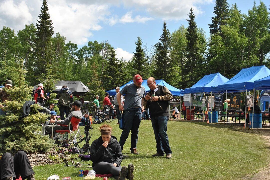 A group of people are standing in a field with blue tents.