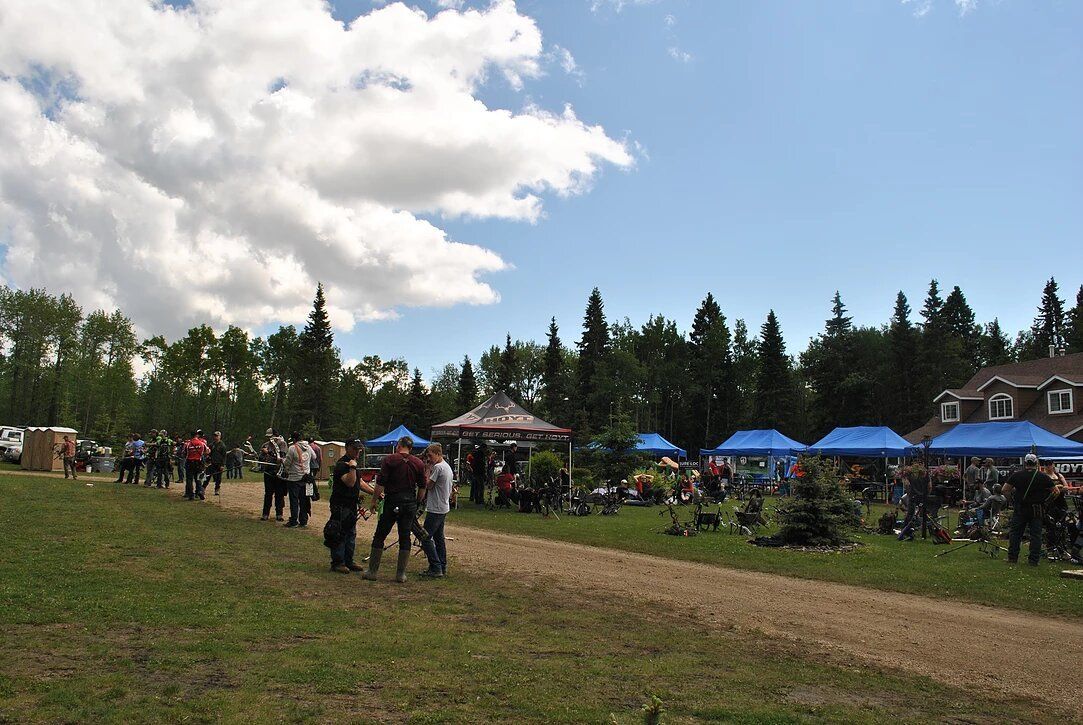 A group of people are standing in a field with blue tents.