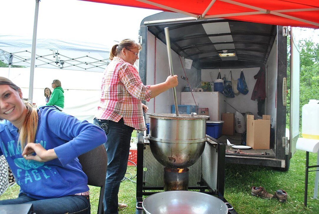 Two women are preparing food in front of a trailer.