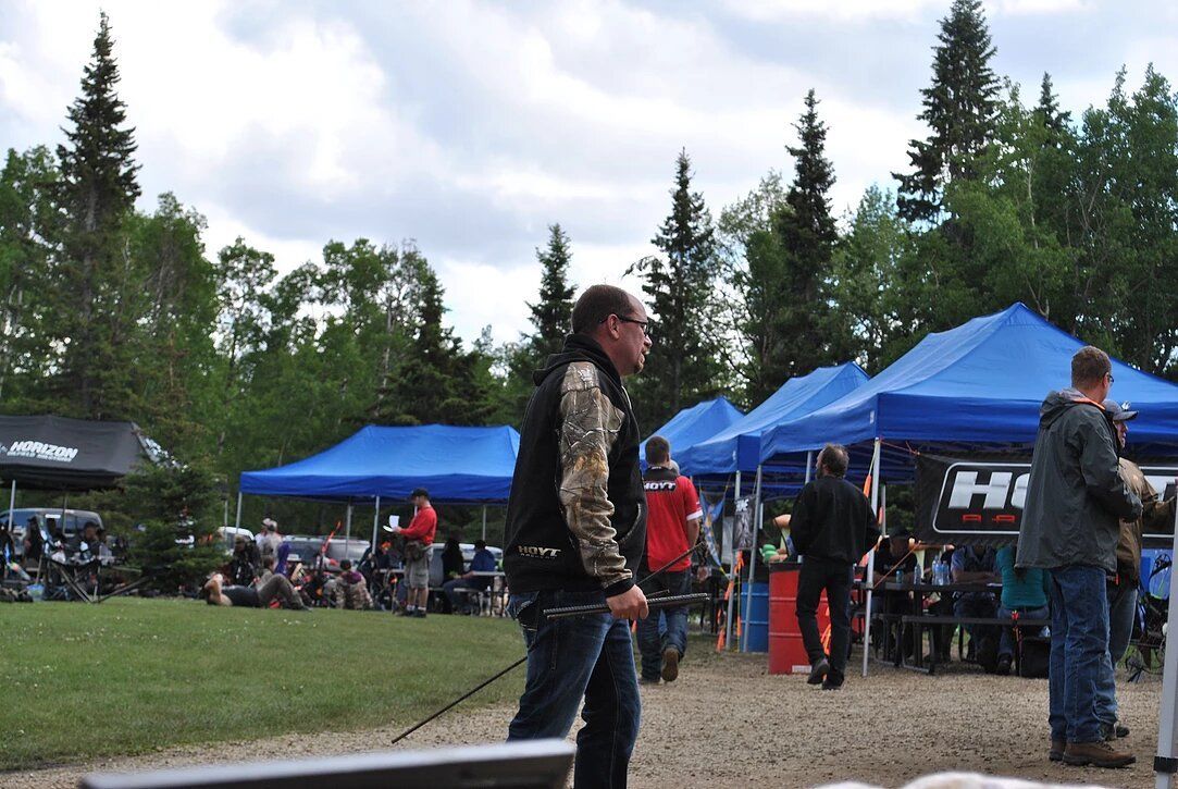 A man stands in front of a row of blue tents with the word hi on them