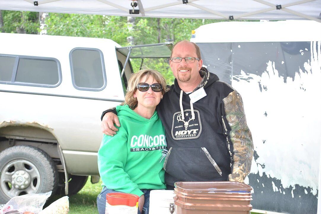 A man and a woman are posing for a picture in front of a truck.