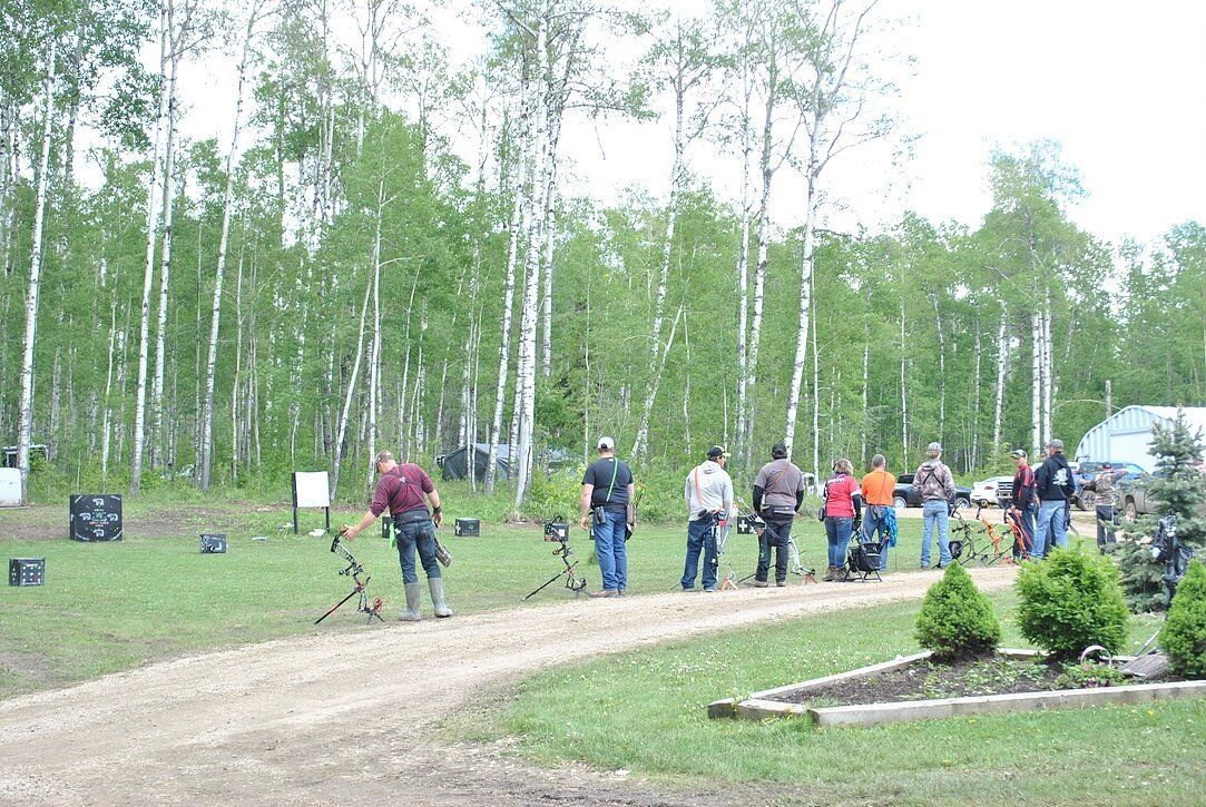 A group of people are standing on a dirt road in the woods.