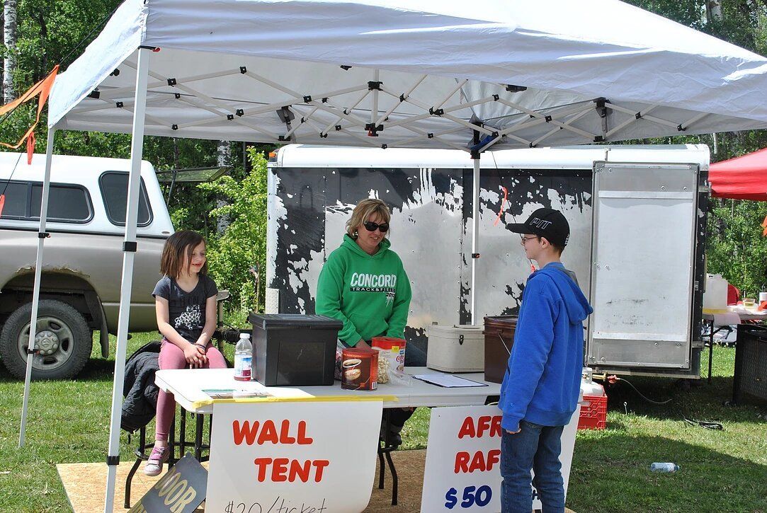 People standing around a table that says wall tent