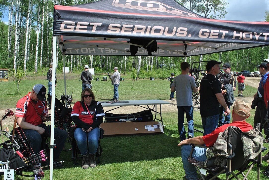 A group of people are sitting under a tent that says get serious get ready.