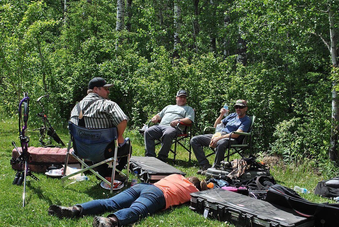 A group of people are sitting in chairs in the grass.