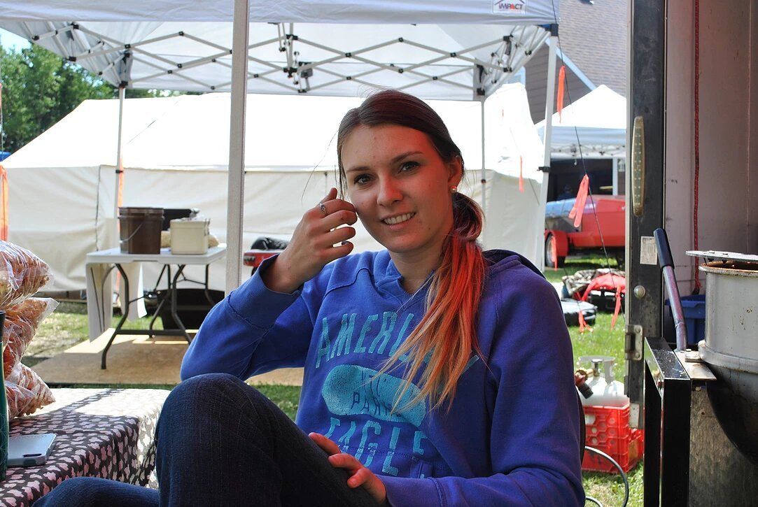A woman in a blue sweatshirt is sitting under a tent